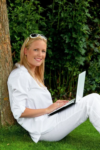 Vrouw met laptopcomputer in de tuin — Stockfoto