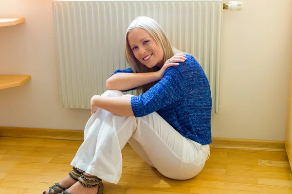 Woman sitting in front of a radiator — Stock Photo, Image