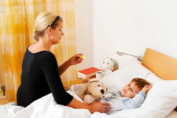 Moeder en ziek kind in bed. griep. — Stockfoto