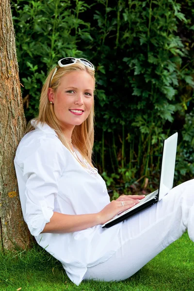 Vrouw met laptopcomputer in de tuin — Stockfoto