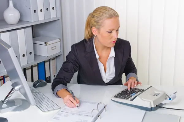 Mujer en oficina con calculadora — Foto de Stock