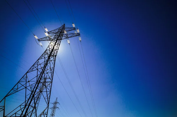 Pilón de electricidad contra el cielo azul con sol — Foto de Stock