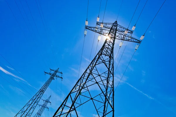 Pilón de electricidad contra el cielo azul con sol — Foto de Stock