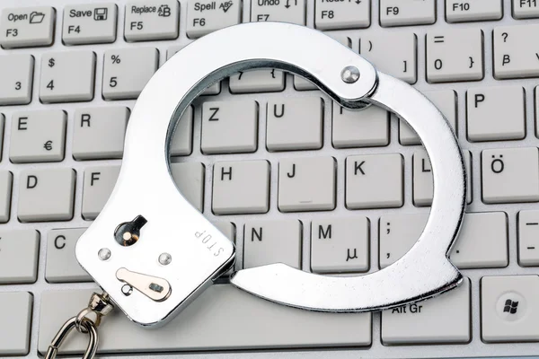 Handcuffs on computer keyboard — Stock Photo, Image