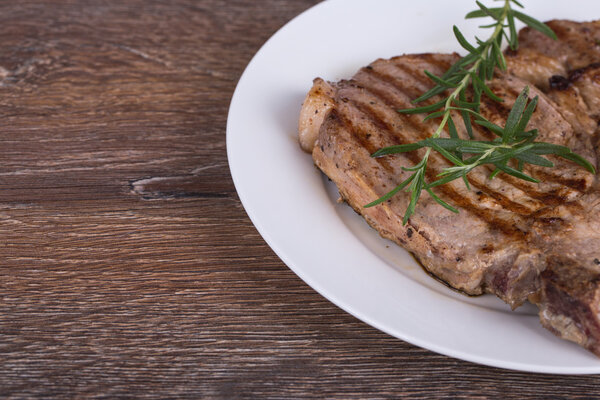 Grilled steak with rosemary on wooden background