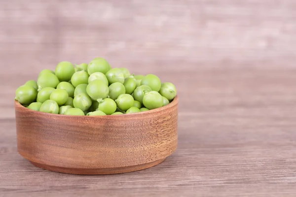 Guisantes en un tazón de madera — Foto de Stock