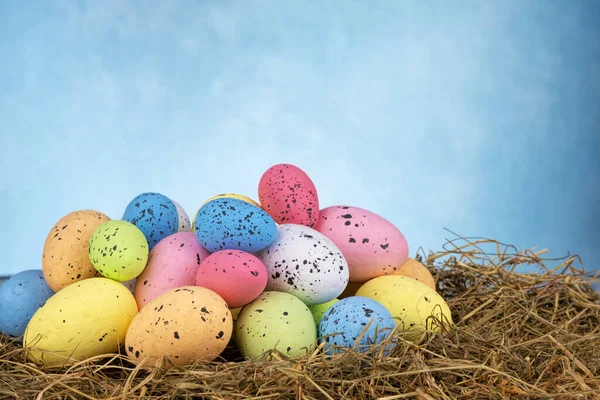 Colorate uova di Pasqua su erba secca su sfondo azzurro cielo — Foto Stock