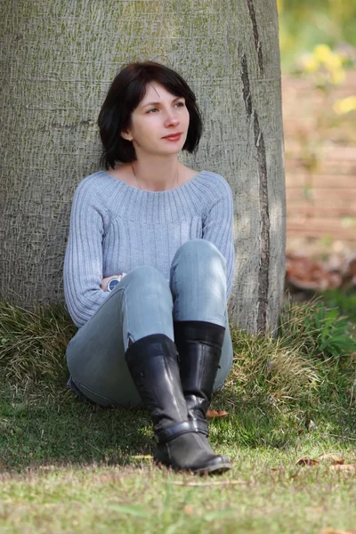 Frau sitzt unter dem Baum — Stockfoto