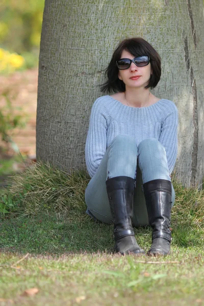 Frau sitzt unter dem Baum — Stockfoto