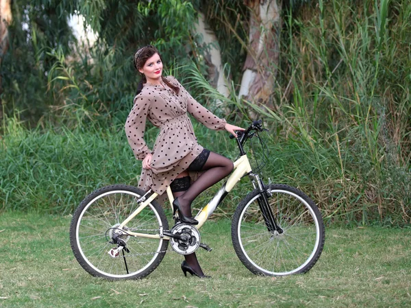 Pin-up girl poising on a bike — Stock Photo, Image