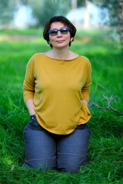 Kobieta siedzi na zielonej trawie — Zdjęcie stockowe
