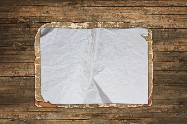Folha de papel enrugada em um fundo de madeira — Fotografia de Stock
