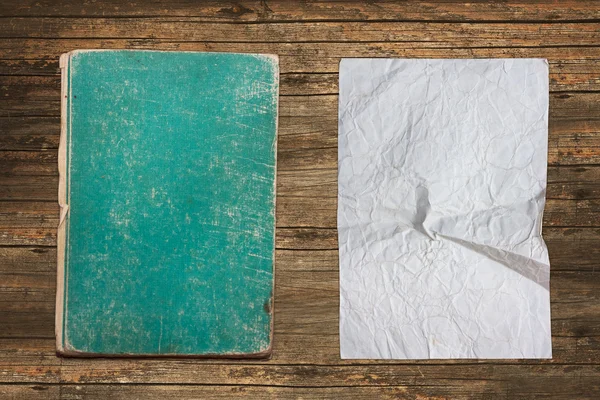 Старая книга и мятая бумага на деревянном фоне — стоковое фото