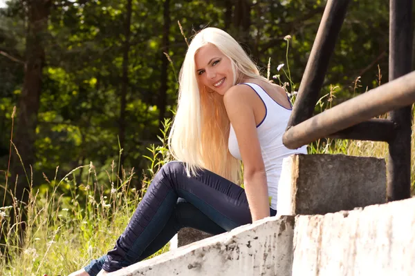 Uśmiechający się blond dama siedząc na schodach odkryty — Zdjęcie stockowe