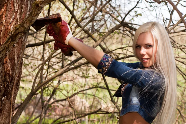 Sexy blond model with an axe in the forrest — Stock Photo, Image