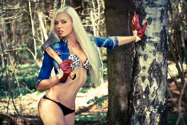 Sexy modelo rubio con un hacha en el bosque —  Fotos de Stock