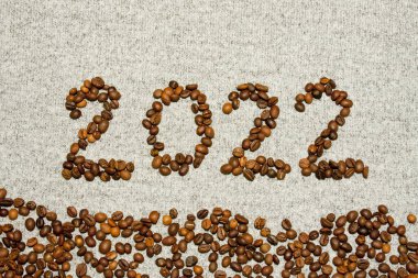 Gri örülmüş arka planda kahve çekirdeklerinden yapılmış 2022 numara. Kartpostal Mutlu Noeller ve mutlu yıllar
