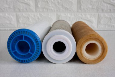 Su arıtma için kullanılan kartuşlar. Mekanik kirlilik, klor ve inorganik kirlilikten su arındırma için ev yapımı ters osmoz sistemi için üç fişek. Yakın çekim