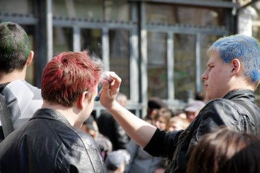 Odessa, Ukrayna - 1 Nisan 2011: 1 Nisan 'da Odesa Tatili - Humorina 1 Nisan 2011' de Odessa, Ukrayna 'da. Şehir caddesinde, erkek kuaför başka bir gencin saçını sprey boyayla kırmızıya boyuyor..