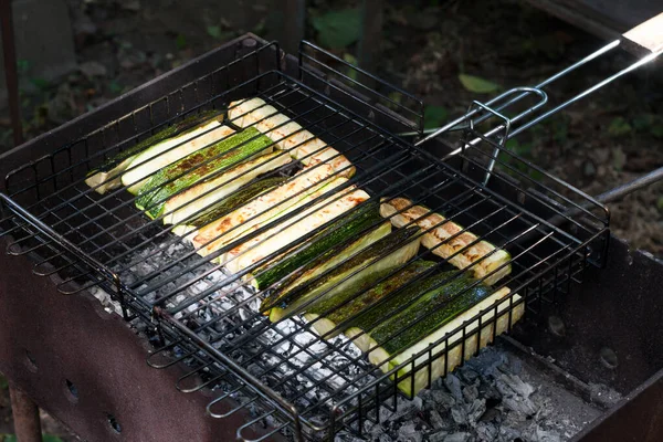 Grilled zucchini. Cooking an appetizing dish grill grate with slices of zucchini over coals on grill. Seasonal summer dish. Outdoor. selective focus