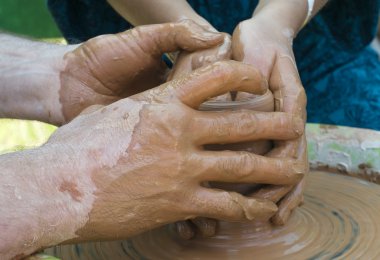 Bir çömlekçinin elleri, çemberin üzerinde toprak kavanozu yaratıyor.