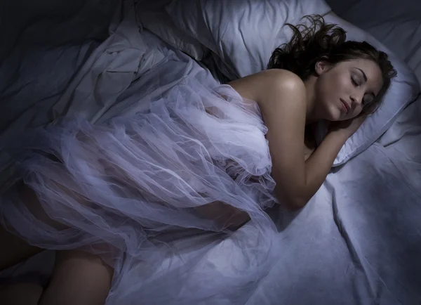 Молода жінка спить вночі в ліжку — стокове фото