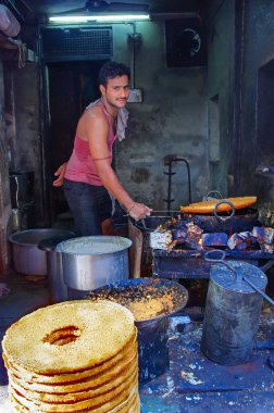 Tanımlanamayan sokak satıcısı bir pazarda yemek yapıyor.