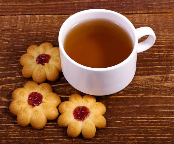 Xícara de chá com flores biscoito no fundo de madeira — Fotografia de Stock