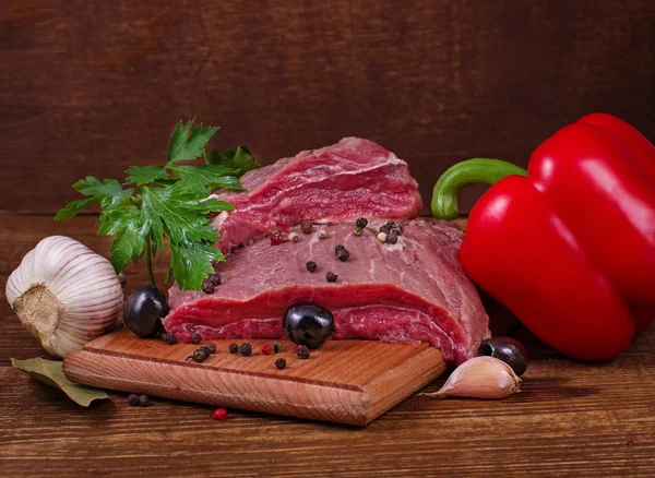 Carne crua e especiarias no fundo de madeira — Fotografia de Stock