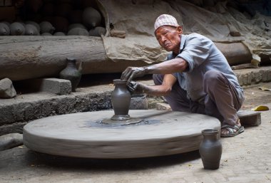 Nepalese  potter working in pottery workshop clipart