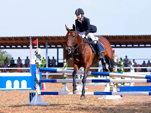 Saltar sobre un caballo rojo a través de un obstáculo. — Foto de Stock