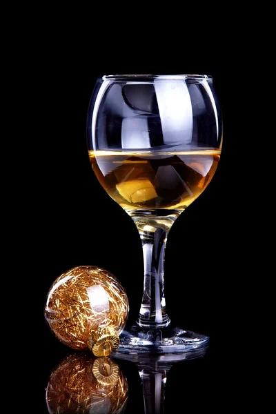 Glass with drink and a Christmas ball. — Stock Photo, Image