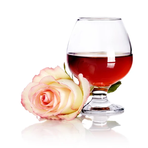 Glass with alcohol and rose on a white background. — Stock Photo, Image