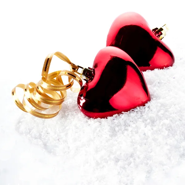 Dos corazones rojos con cintas de oro en la nieve — Foto de Stock