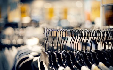 Marketten alışveriş. Mağazadaki askılarda satılık giysiler. Bulanık arkaplan. Bir butikte şık elbiseler giyersin. Piyasada çeşitli giysiler.