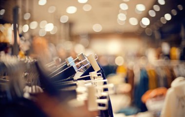 Marketten alışveriş. Mağazadaki askılarda satılık giysiler. Bulanık arkaplan. Bir butikte şık elbiseler giyersin. Piyasada çeşitli giysiler.