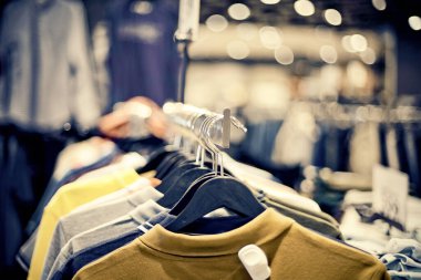 Marketten alışveriş. Mağazadaki askılarda satılık giysiler. Bulanık arkaplan. Bir butikte şık elbiseler giyersin. Piyasada çeşitli giysiler.