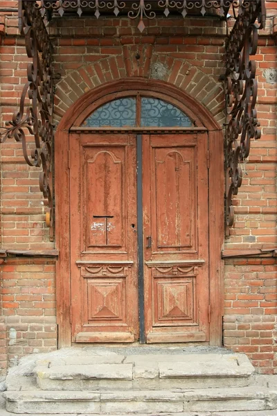 Oude houten deur in een baksteen gebouw — Stockfoto