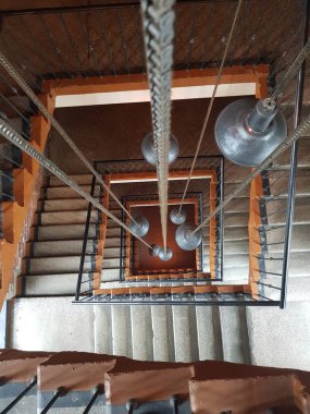 Merdiven boşluğunda yanan lambalar asılı.