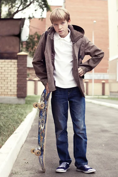 Школьный подросток со школьной сумкой и скейтбордом — стоковое фото