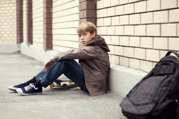 School tiener met scholbag en skateboard — Stockfoto