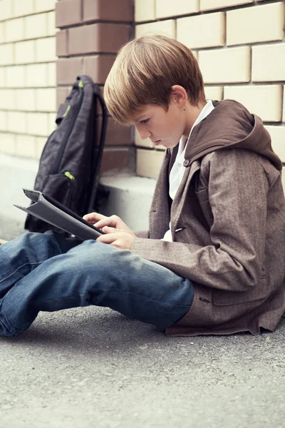 Escola adolescente com tablet eletrônico sentado — Fotografia de Stock