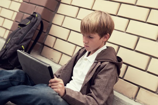École adolescent avec tablette électronique assis — Photo
