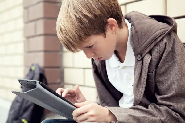 Escuela adolescente con electrónica tableta sentado — Foto de Stock