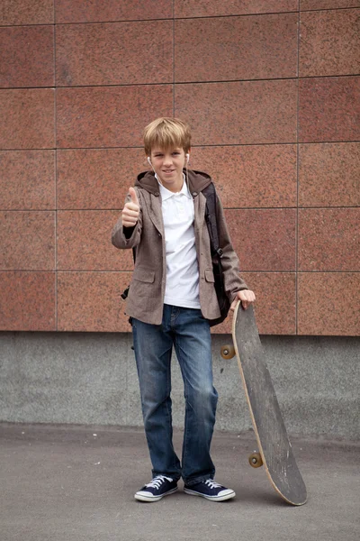 Школьный подросток со школьной сумкой и скейтбордом — стоковое фото