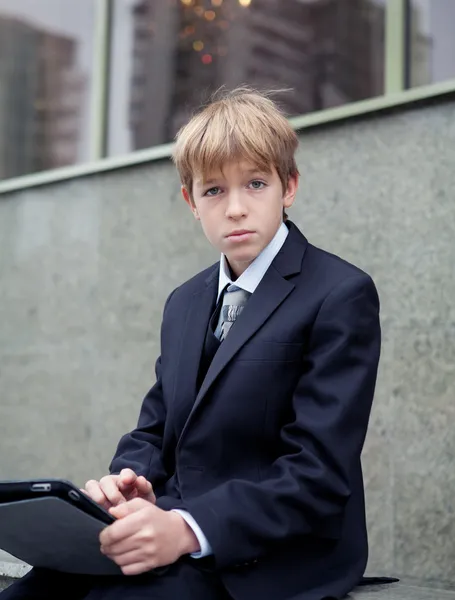 Skola pojke med elektroniska tablett sitter, — Stockfoto