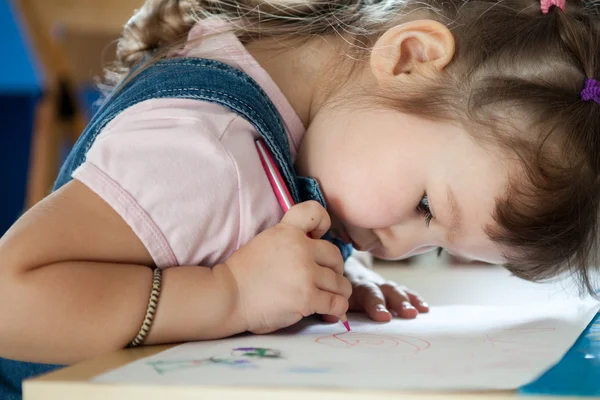 Schattig klein meisje is tekenen met pen in voorschoolse — Stockfoto