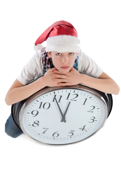 Teenager in cap of Santa Claus and large clock — Stock Photo, Image