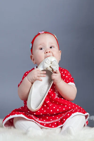 Kis lány piros ruhában gazdaság cipő — Stock Fotó