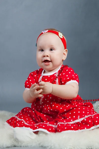 Little girl in red dress sitting near Christmas tree — Stock Photo, Image